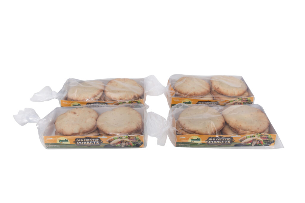 Freshly baked Old Country Pockets pocket bread from Breadmasters - Traditional thicker, denser pita bread arranged artfully on a rustic surface, showcasing the soft, fluffy texture and golden-brown color | Made with time-honored methods for authentic Mediterranean meals