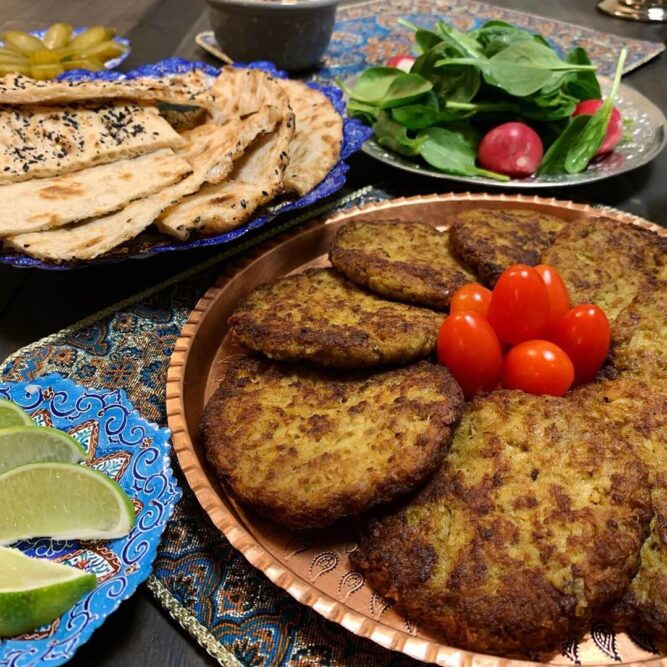 Persian-Kotlet-with-Sangak-and-Lime-Breadmasters - Breadmasters Persian Kotlet cutlets served with ARA-Z Sangak flatbread, fresh herb salad, and lime wedges - Traditional Iranian meat patties alongside toasted sangak and bright citrus garnish | Authentic Persian meal presentation from Breadmasters
