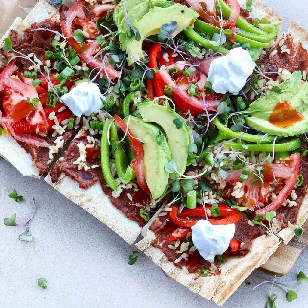 Refried Beans and Avocado flatbread pizza made with Markook Thinnest Flatbread - Crispy base topped with creamy refried beans, fresh avocado slices, cilantro, and a drizzle of sauce | Perfect for quick vegetarian lunch or dinner | Breadmasters recipe