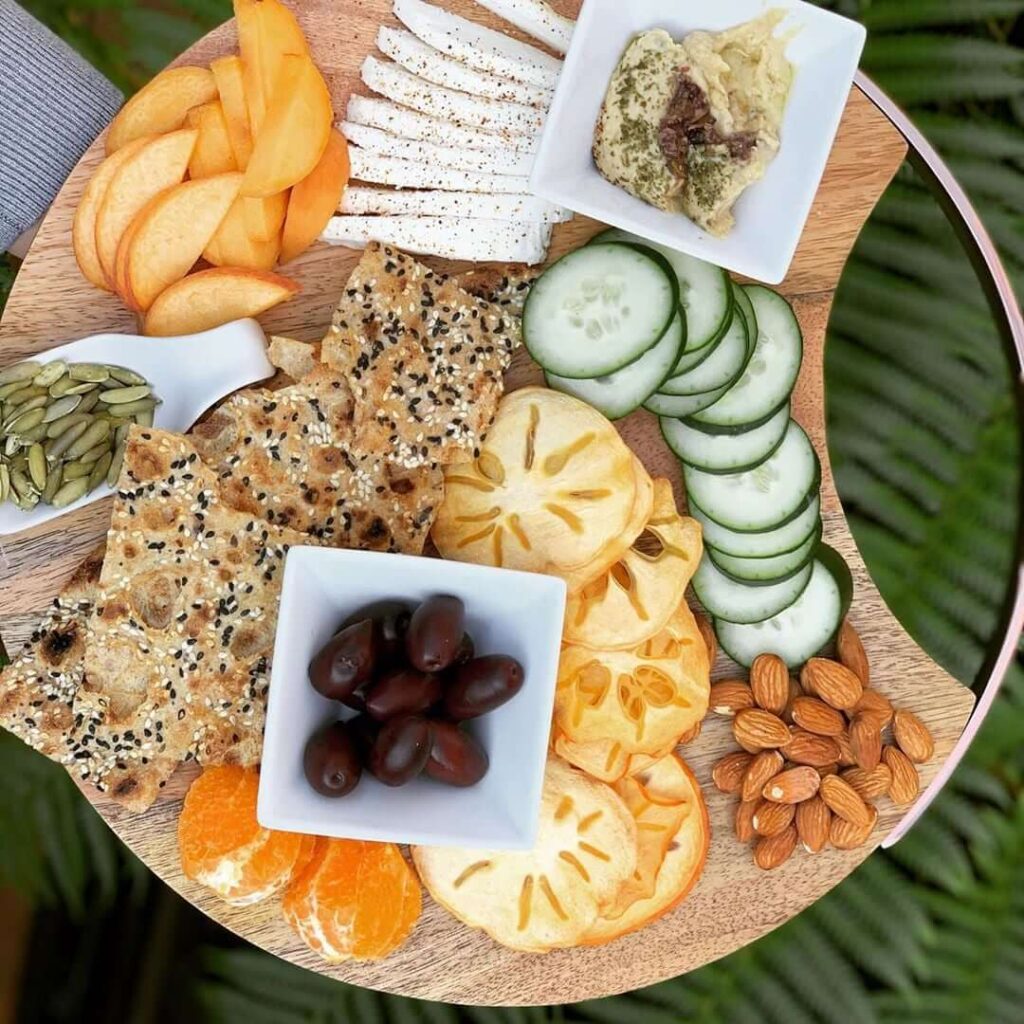 Sangak Crisps Charcuterie Board - BreadMasters Sangak multi-seed crisps on charcuterie board with cheese, persimmon, cucumber, almonds, and olives